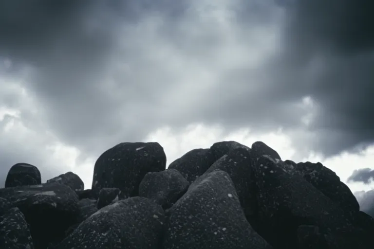 A towering stone structure stands against a cloudy sky, its sharp edges softened by a diffuse glow. The atmosphere is serious, with a hint of somber reverence.
